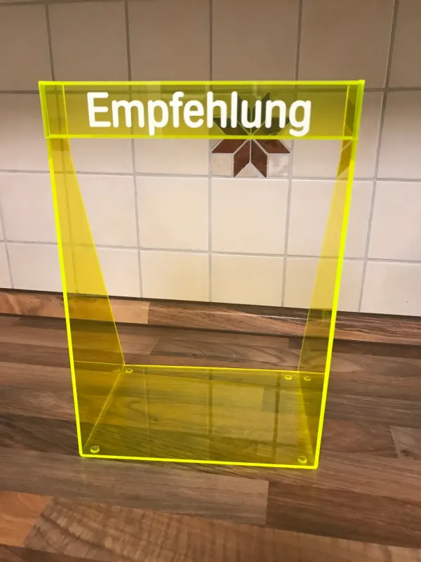 Thekendisplay aus gelb fluoreszierendem Acrylglas mit Schriftzug Empfehlung
